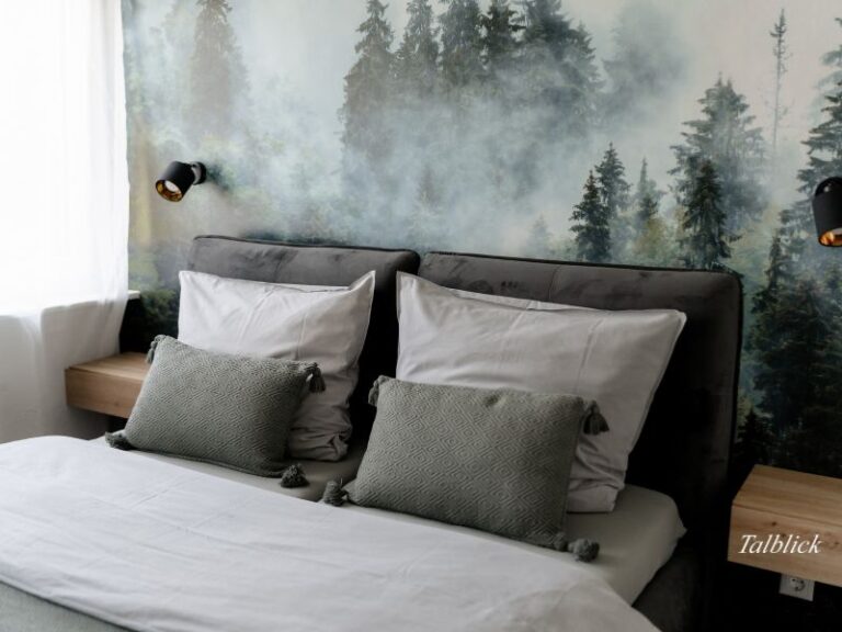 Doppelbett vor einer Wandtapete mit Nebelwald